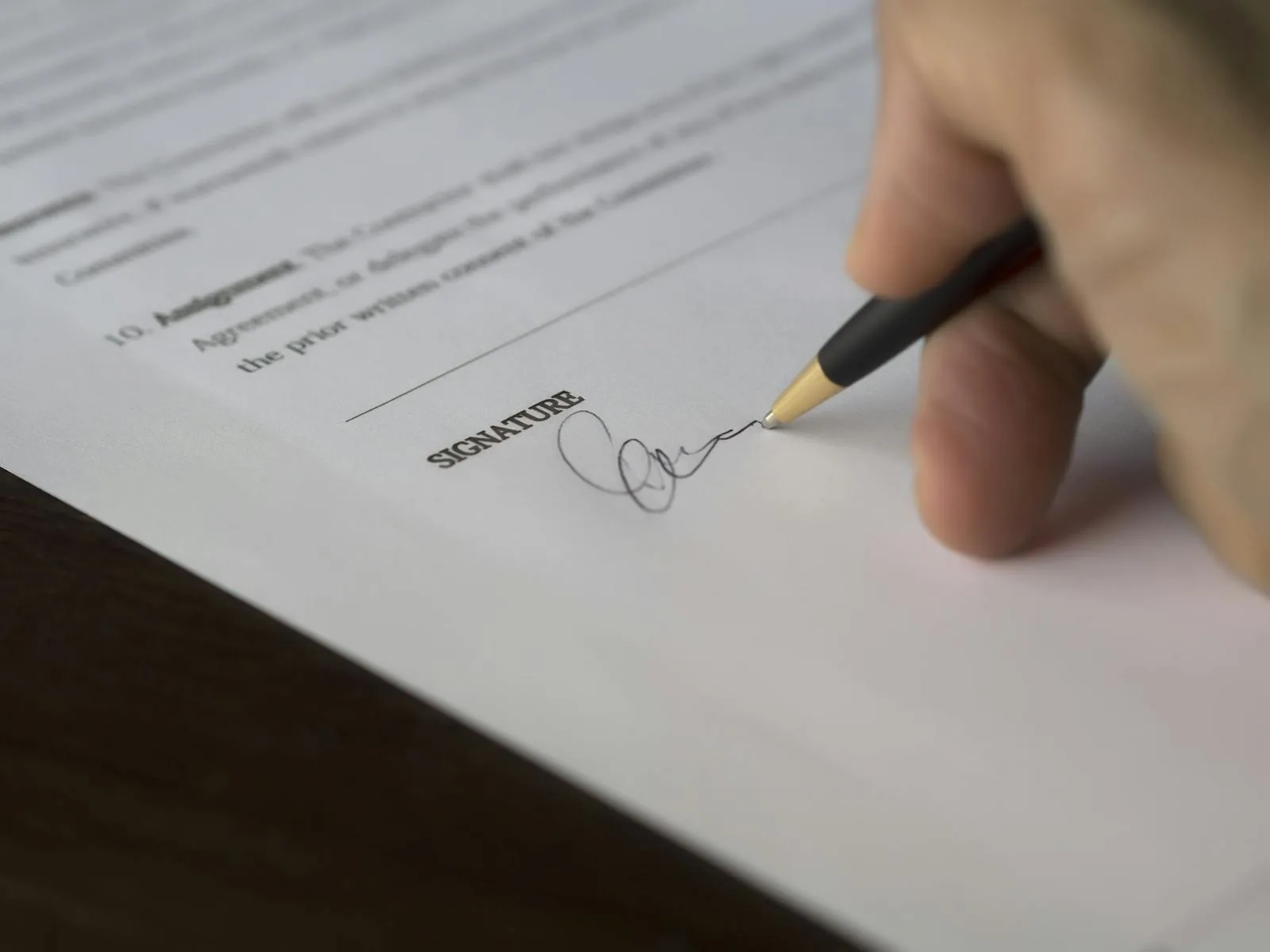 Hand som signerar ett kontrakt med en penna — symbolen för att läsa det finstilta innan du tecknar en hemsida utan bindningstid.